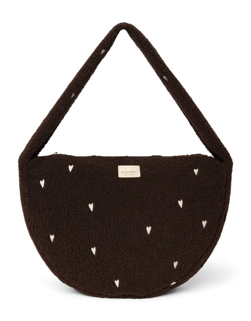 Schokoladenbraune Cross Body Umhängetasche Chocolate Teddy Hearts von Studio Noos aus weichem Teddy-Material und aufgestickten weißen Herzen mit Seitentaschen und Platz für einen 13-Zoll-Laptop.
