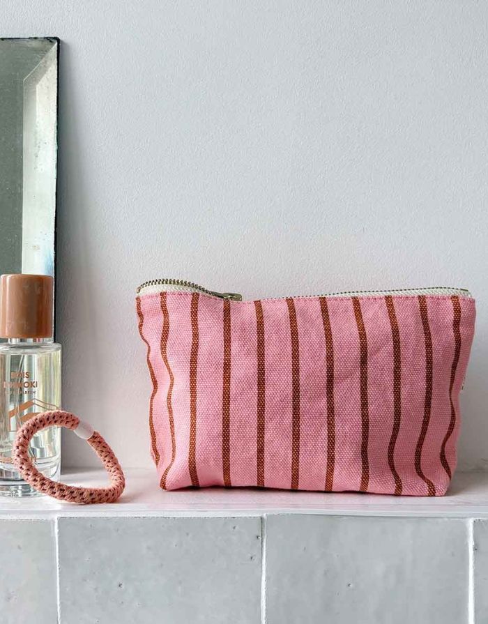 Kosmetiktasche Sofia von Rose in April in Rosa mit braunen Streifen im Badezimmer neben einem rosa Zopfgummi