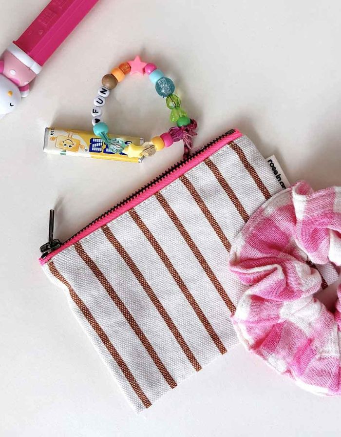 Kleine Tasche für Kosmetik oder Geld von Rose in April in Beige mit braunen Streifen mit einem Scrunchie daneben