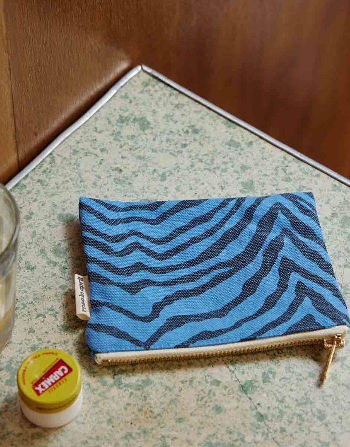 Kleine Tasche für Kosmetik oder Geld von Rose in April in Blau mit schwarzem Zebra Muster auf einer Unterlage