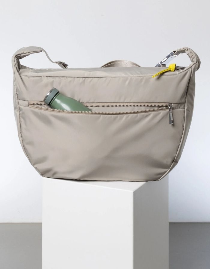 Padded Hip Bag Oversized von Vivi Mari in Stone, große wasserabweisende Umhängetasche mit zwei Außentaschen, verstellbarem Schultergurt und silbernen Metallakzenten, aus recyceltem Polyester.