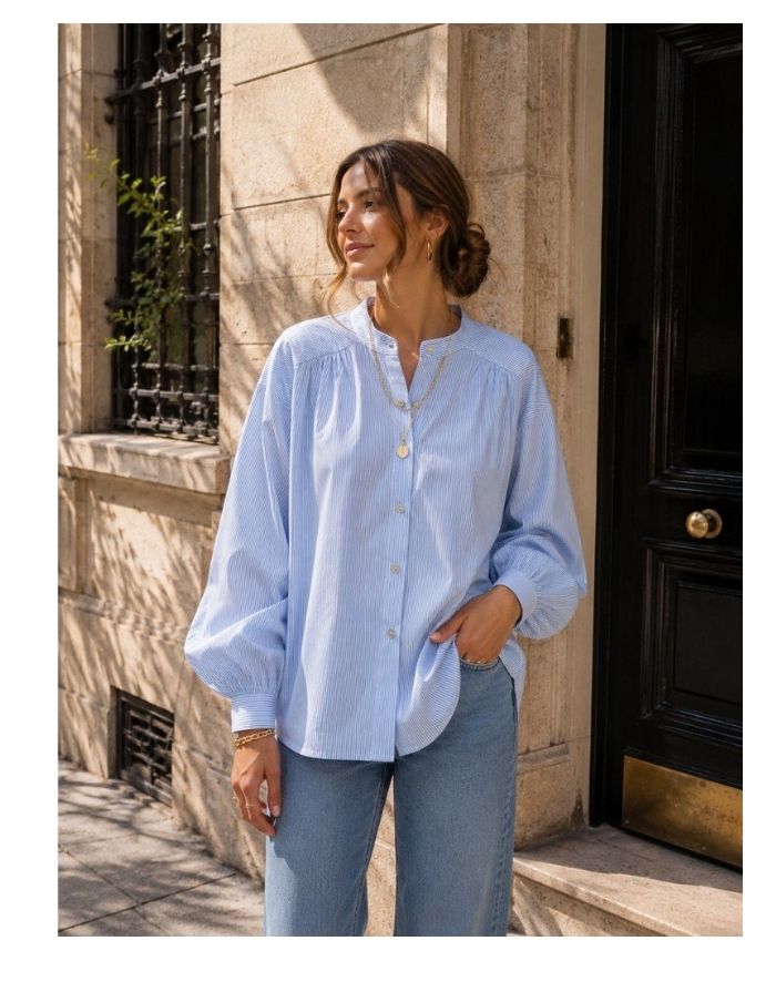 Gestreifte Bluse Striped Light Blue von MAËLYS PARIS mit Rundhalsausschnitt, Raffungen an den Schultern und langen Ärmeln.