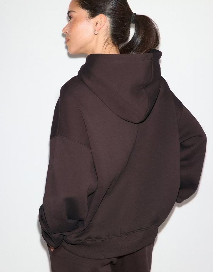Gina Tricot Iconic Hoodie in Chocolate Plum mit Oversize-Passform, Kängurutasche und gefütterter Kapuze am Model von hinten