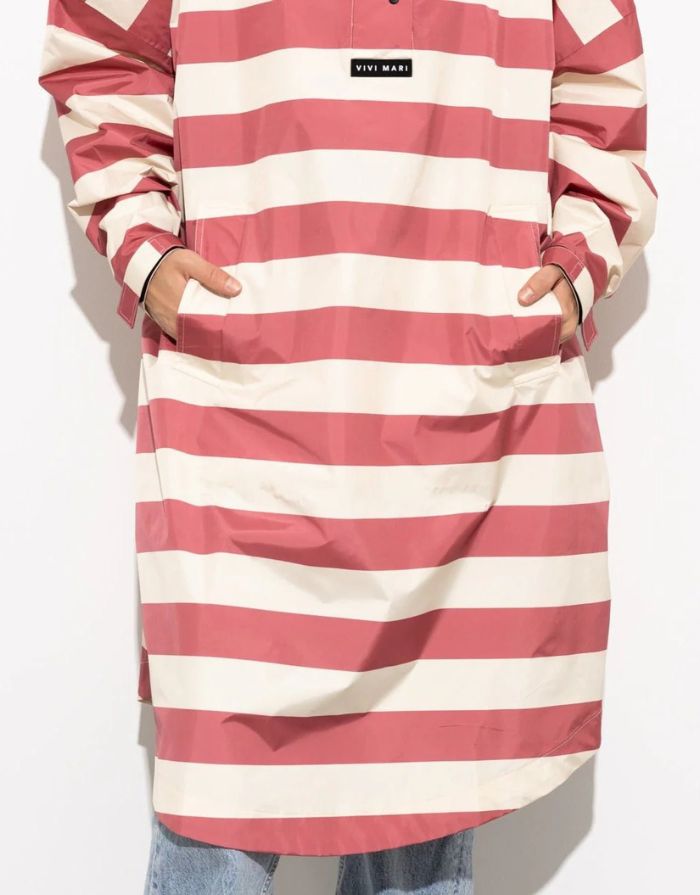 Raincoat Bold Stripes Blush/Sand von VIVI MARI: Langer, wasserdichter Regenmantel im Streifen-Design, oversized geschnitten mit Kapuze, Knopfleiste, Klettverschluss-Manschetten und praktischen Taschen – nachhaltig aus recyceltem Polyester gefertigt.