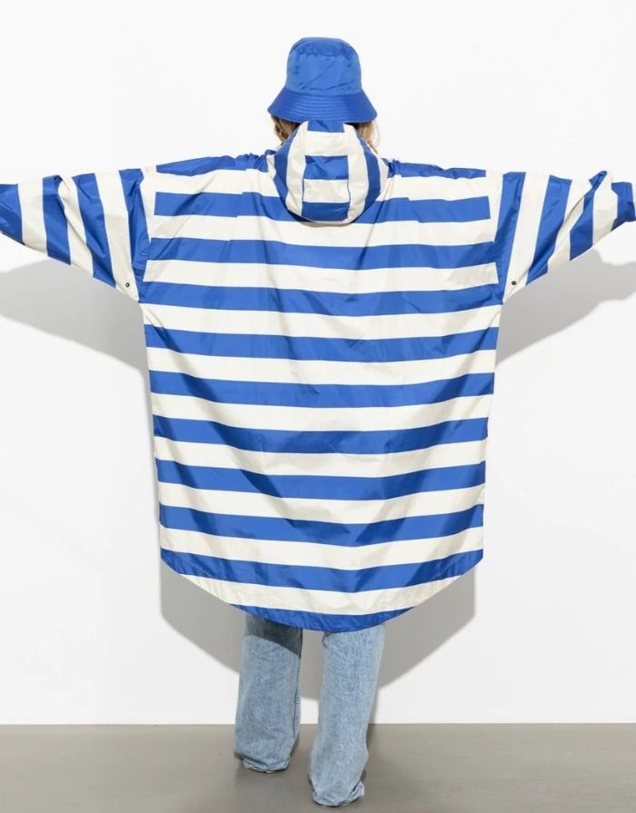 Raincoat Bold Stripes Blue/Sand von VIVI MARI – wasserdichtes Cape aus recyceltem Polyester in Oversize-Passform mit Kapuze, Klettverschluss-Manschetten und seitlichen Taschen, nachhaltig und funktional für Stadt, Fahrrad und Alltag