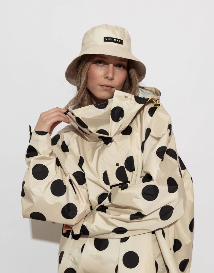 Raincoat Bold Stripes Dots Black/Sand von VIVI MARI: Langer, wasserdichter Regenmantel im Streifen-Design, oversized geschnitten mit Kapuze, Knopfleiste, Klettverschluss-Manschetten und praktischen Taschen – nachhaltig aus recyceltem Polyester gefertigt.