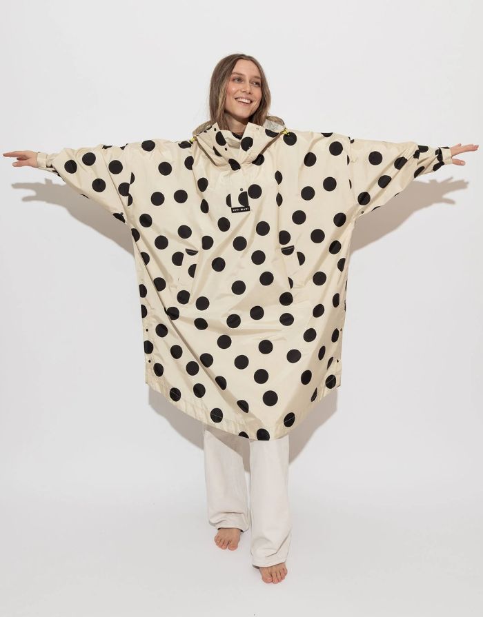 Raincoat Bold Stripes Dots Black/Sand von VIVI MARI: Langer, wasserdichter Regenmantel im Streifen-Design, oversized geschnitten mit Kapuze, Knopfleiste, Klettverschluss-Manschetten und praktischen Taschen – nachhaltig aus recyceltem Polyester gefertigt.