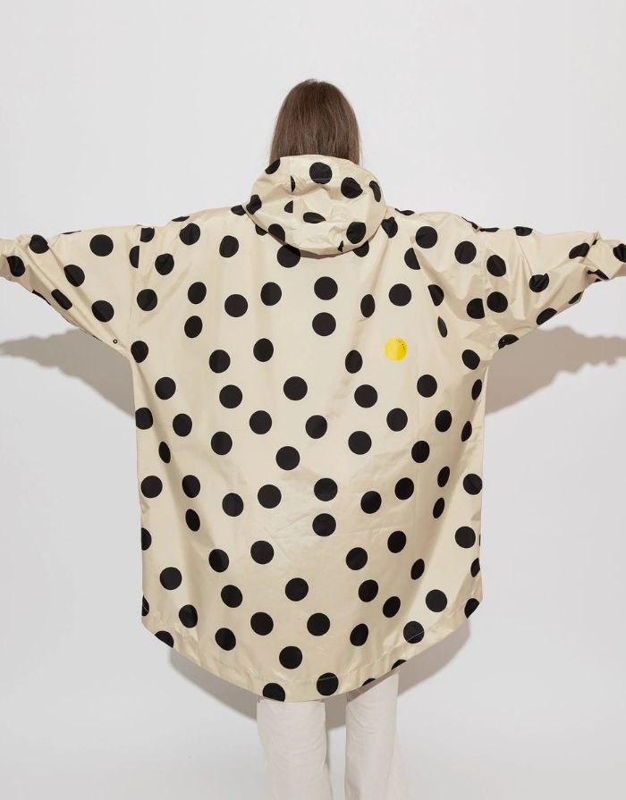 Raincoat Bold Stripes Dots Black/Sand von VIVI MARI: Langer, wasserdichter Regenmantel im Streifen-Design, oversized geschnitten mit Kapuze, Knopfleiste, Klettverschluss-Manschetten und praktischen Taschen – nachhaltig aus recyceltem Polyester gefertigt.