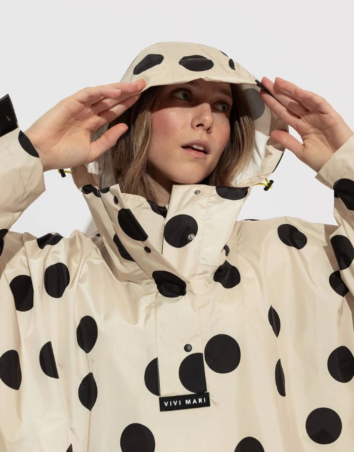 Raincoat Bold Stripes Dots Black/Sand von VIVI MARI: Langer, wasserdichter Regenmantel im Streifen-Design, oversized geschnitten mit Kapuze, Knopfleiste, Klettverschluss-Manschetten und praktischen Taschen – nachhaltig aus recyceltem Polyester gefertigt.