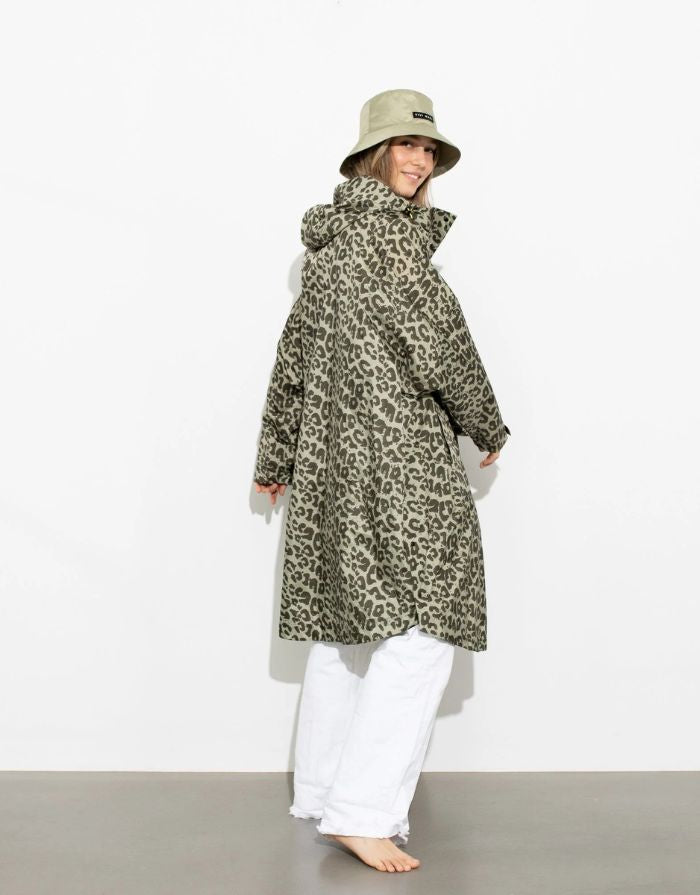 Raincoat Leo Splashes Navy Oliv von VIVI MARI: Langer, wasserdichter Regenmantel im Streifen-Design, oversized geschnitten mit Kapuze, Knopfleiste, Klettverschluss-Manschetten und praktischen Taschen – nachhaltig aus recyceltem Polyester gefertigt.