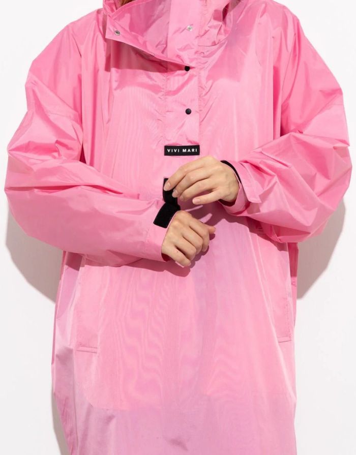 Raincoat Bold Stripes Soft Pink von VIVI MARI: Langer, wasserdichter Regenmantel im Streifen-Design, oversized geschnitten mit Kapuze, Knopfleiste, Klettverschluss-Manschetten und praktischen Taschen – nachhaltig aus recyceltem Polyester gefertigt.