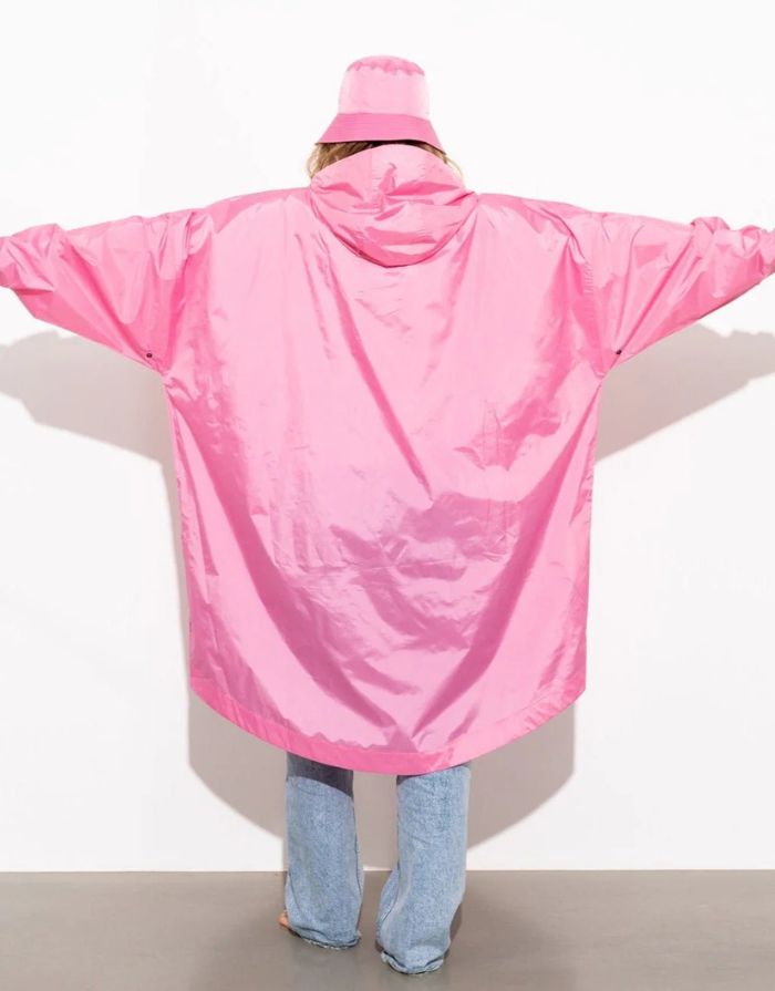 Raincoat Bold Stripes Soft Pink von VIVI MARI: Langer, wasserdichter Regenmantel im Streifen-Design, oversized geschnitten mit Kapuze, Knopfleiste, Klettverschluss-Manschetten und praktischen Taschen – nachhaltig aus recyceltem Polyester gefertigt.