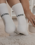 Weiße Socken Erstmal Kaffee von Eulenschnitt mit schwarzem Schriftzug an der Ferse und schwarzen Details