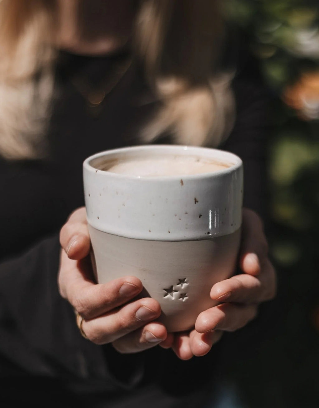 Handgefertigter Steingutbecher Sterne von Eulenschnitt mit eingeprägten Sternen Motiv und einem Fassungsvermögen von ca. 320 ml in der Hand mit Kaffee