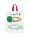Turtle & Dolphin Haarspangen von Rockahula mit Schildkröten- und Delfin-Motiv auf gepunkteten, stoffbezogenen Klickspangen.