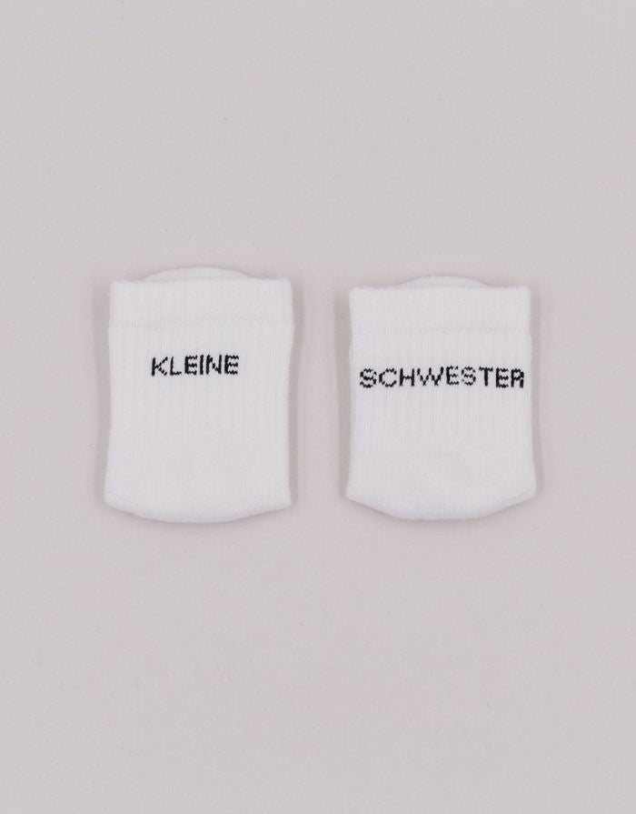 Babysocken Kleine Schwester von Eulenschnitt, 80% Baumwolle, 18% Polyamid, 2% Elastan, mit Schriftzug „Kleine Schwester“ auf dem Bündchen.