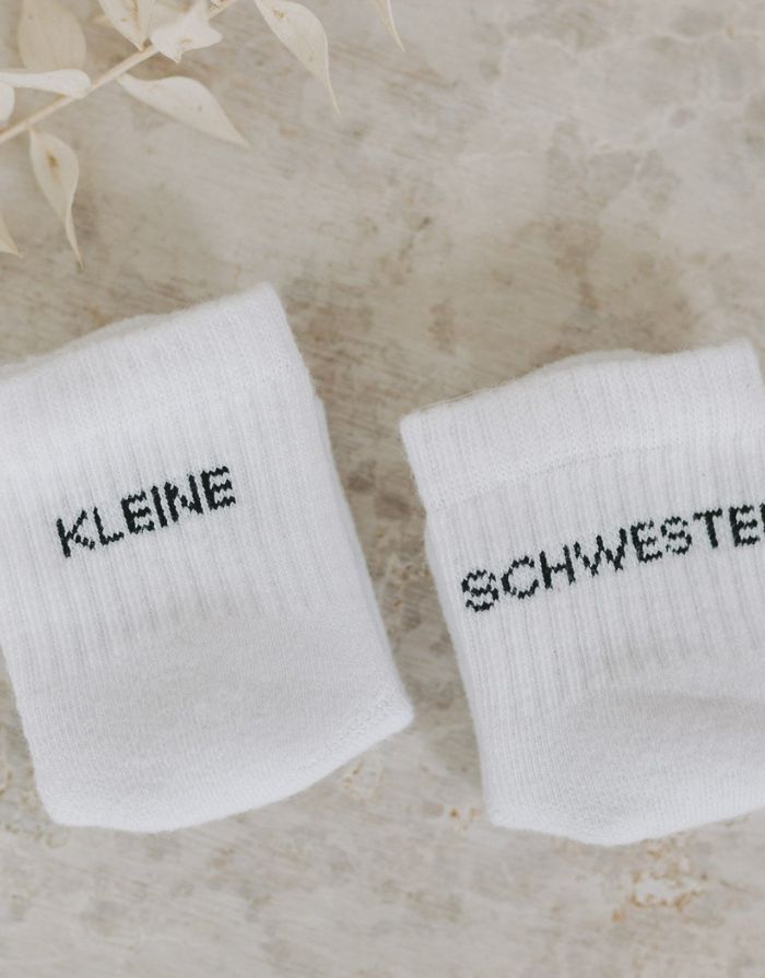 Babysocken Kleine Schwester von Eulenschnitt, 80% Baumwolle, 18% Polyamid, 2% Elastan, mit Schriftzug „Kleine Schwester“ auf dem Bündchen.
