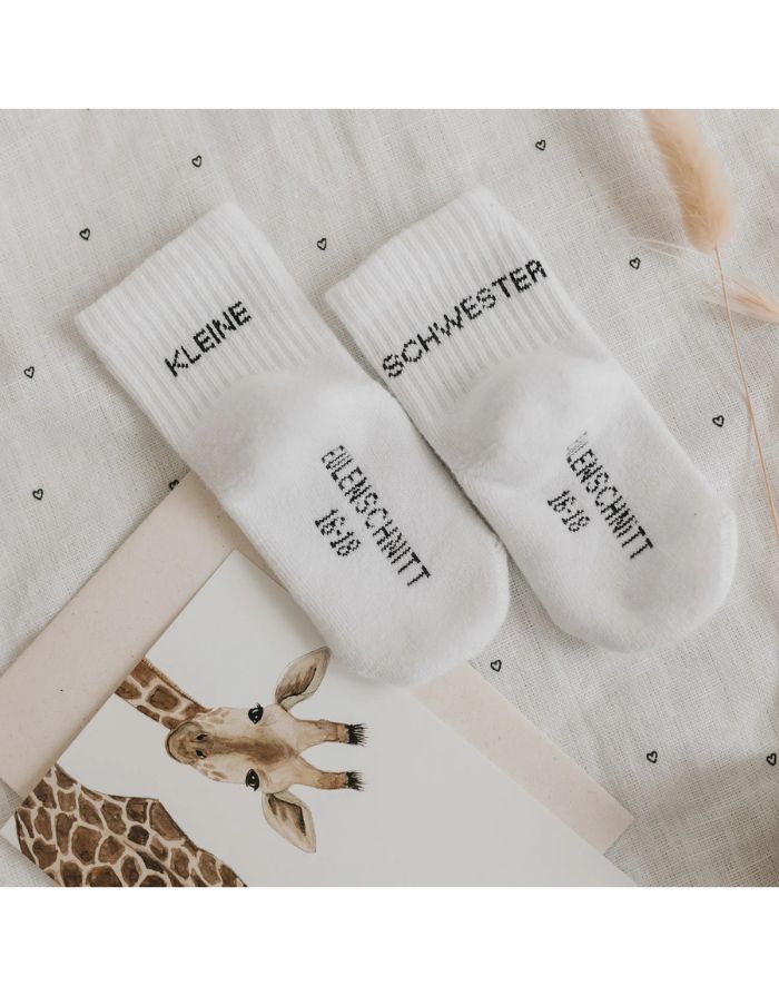 Babysocken Kleine Schwester von Eulenschnitt, 80% Baumwolle, 18% Polyamid, 2% Elastan, mit Schriftzug „Kleine Schwester“ auf dem Bündchen.