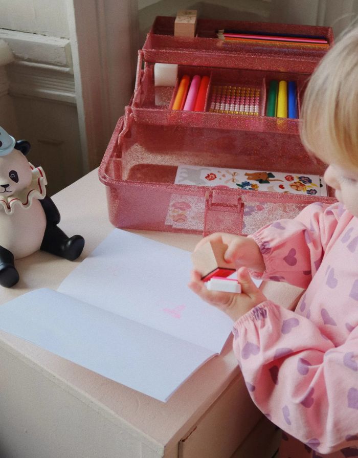 Glitzernder Bastelkoffer in Rosa von Konges Sløjd, gefüllt mit Stiften, Stickern, Stempeln, einem Notizblock und einem kleinen Malbuch – kreatives Set für Kinder.