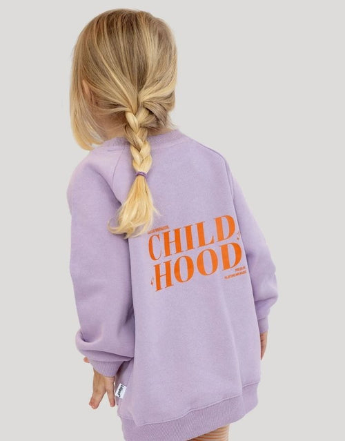 Liliput  Childhood Oversize Sweatshirt für Kinder in Flieder mit kleinem Herz auf der Vorderseite und großem typografischem Rückenprint, am Model.