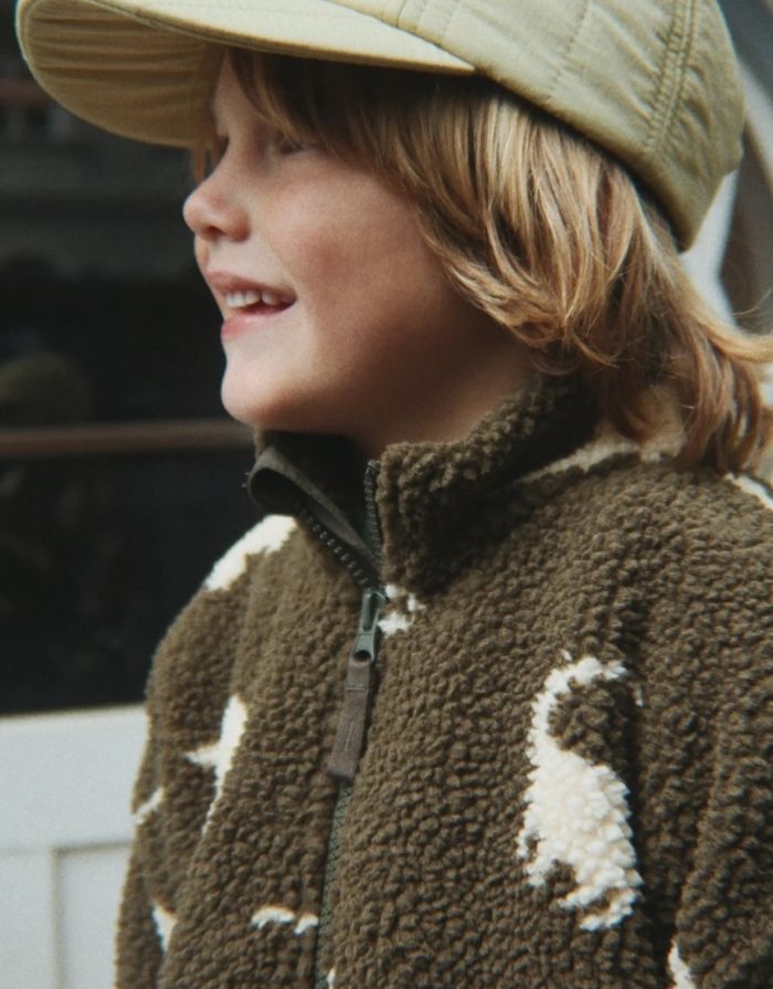 Teddyjacke Jody Dino Silhouette mit weißen Dinosauriern von Konges Sløjd an einem Kind von der Seite
