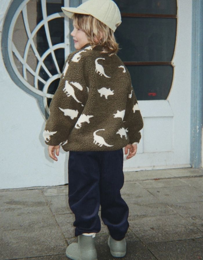 Teddyjacke Jody Dino Silhouette mit weißen Dinosauriern von Konges Sløjd an einem Kind von hinten