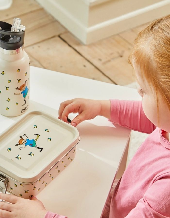 Cremefarbene Pippi Lunchbox von Barbo Toys aus Edelstahl mit klassischer Pippi-Langstrumpf-Illustration und 850 ml Fassungsvermögen mit einem Kind und der passenden Trinkflasche