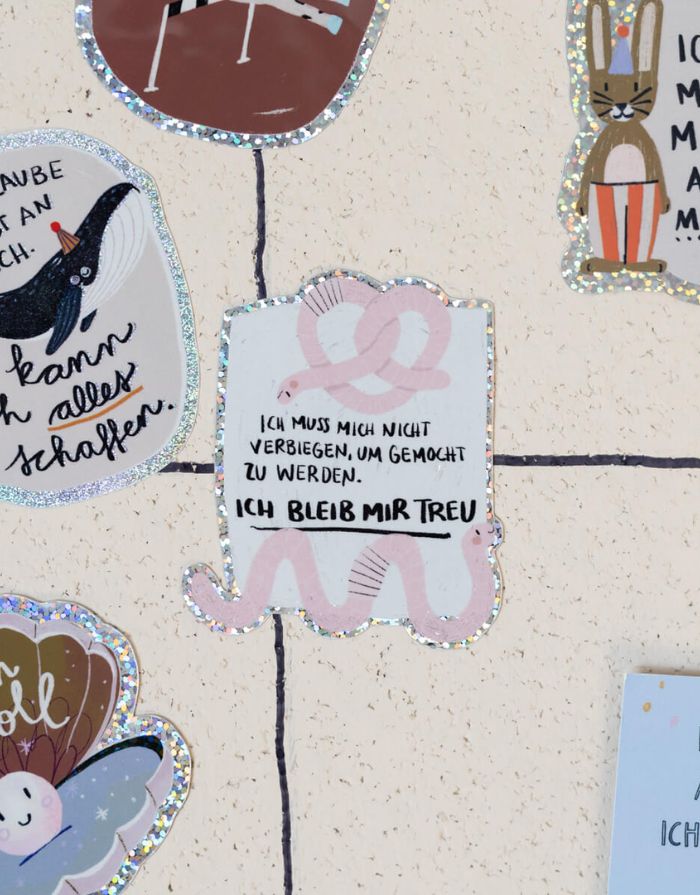 Glitzersticker von Liesels Wicht mit liebevollem Motiv und motivierender Botschaft für Kinder auf glänzendem Glitzervinyl vor einer Wand.