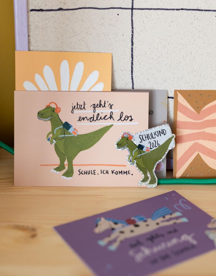 Glitzersticker von Liesels Wicht mit liebevollem Motiv und motivierender Botschaft für Kinder auf glänzendem Glitzervinyl neben einer Postkarte.