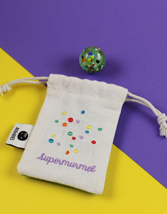 Ava & Yves Supermurmel Grün – Muranoglas-Murmel (25 mm) mit bunten Konfetti-Steinchen im bestickten Stoffbeutel.