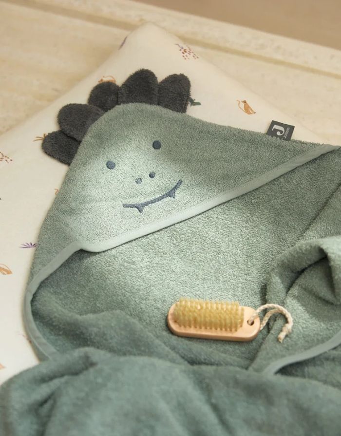 Kapuzenhandtuch von Jollein in der Farbe Grün auf einer Wickelunterlage mit einer Nagelbürste 