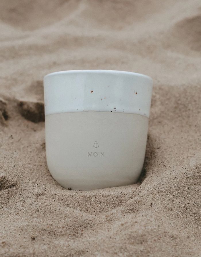 ulenschnitt Steingutbecher Moin mit natürlicher Form und feinen Sprenkeln in handgefertigtem Design im Sand