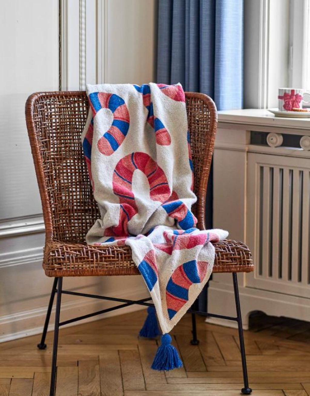 Bunte Candice Decke von Bloomingville in Beige mit geschwungenem Muster in Rot, Blau und Orange sowie blauen Quasten.