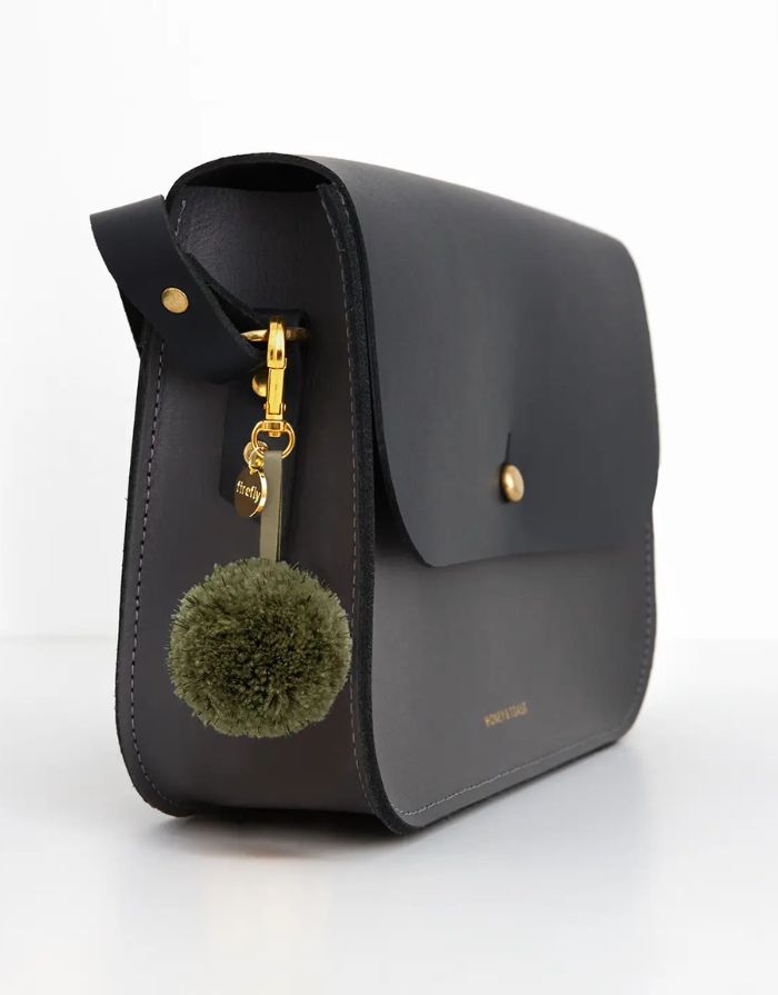 Reflektierender Pom Pom Anhänger in Olivgrün von Firefly Reflectors aus flauschigem Garn mit reflektierendem Faden – dekoratives und sicheres Accessoire für Taschen und Rucksäcke.